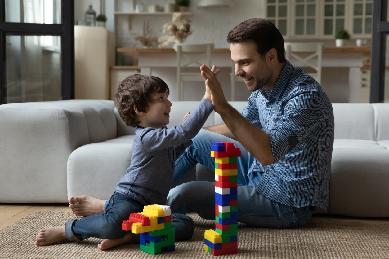 Happy millennial dad giving praise and high five to son
