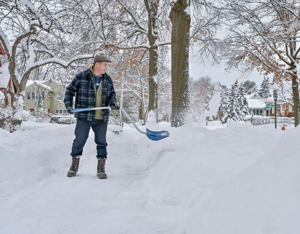 A man shoveling sidewalk in the morning